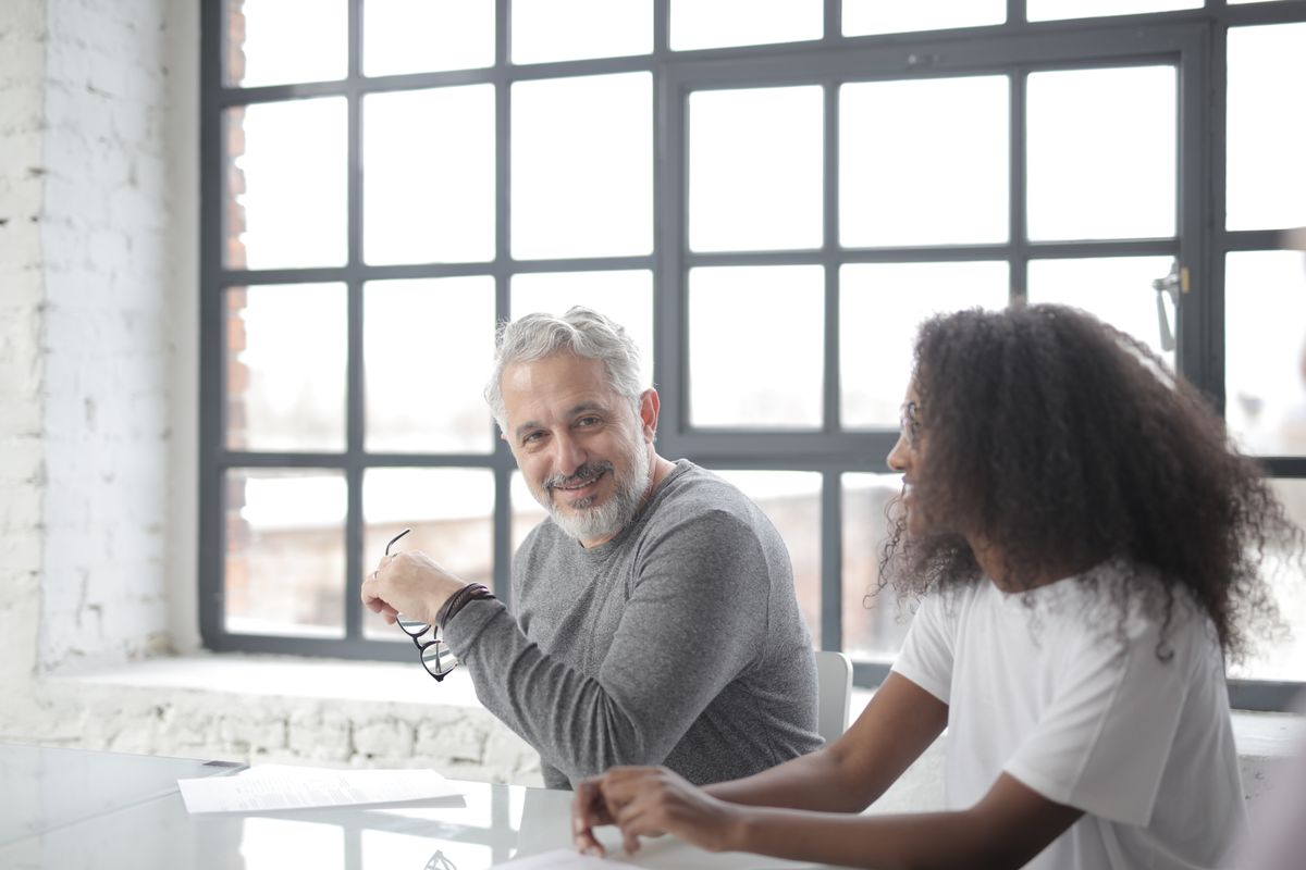 A supportive mentor sitting beside a colleague to help with documents